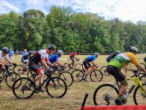 bike riders starting a race on a grass field cyclocross course